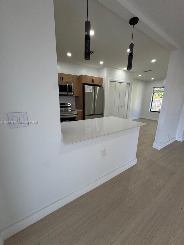 421 SW 11th Ave, Hallandale Beach, FL 33009 - kitchen with stainless steel appliances, wood finished floors, baseboards, brown cabinetry, and recessed lighting