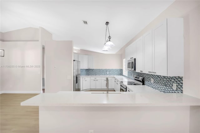 kitchen with appliances with stainless steel finishes, backsplash, light countertops, a sink, and light wood finished floors