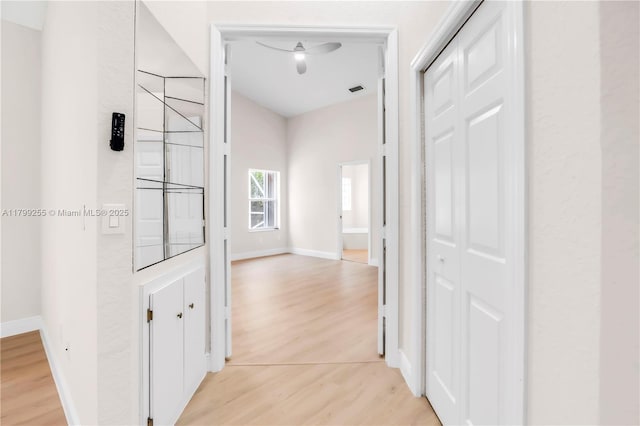 hall featuring light wood-style flooring and baseboards