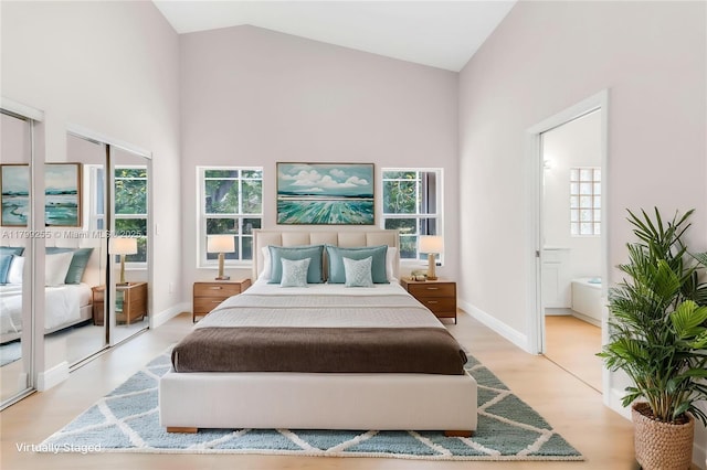 bedroom featuring high vaulted ceiling, ensuite bath, wood finished floors, and baseboards