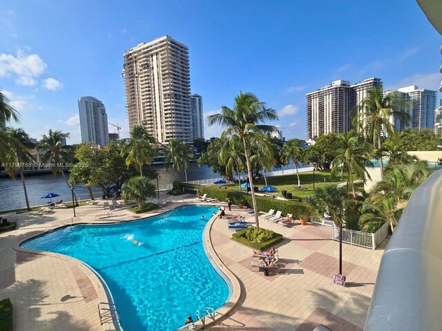 community pool featuring a view of city, a patio, and a water view