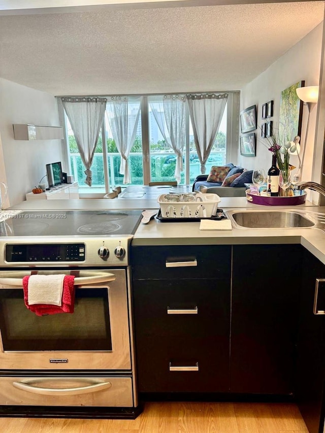 kitchen featuring stainless steel range with electric stovetop, light countertops, plenty of natural light, light wood-style floors, and a textured ceiling