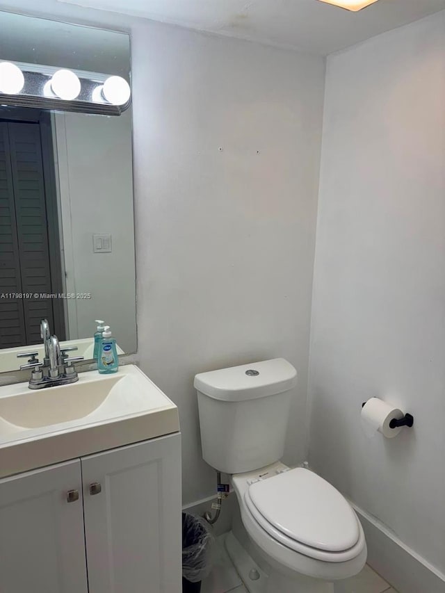 half bathroom featuring toilet, baseboards, vanity, and tile patterned flooring