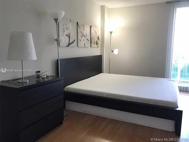bedroom with multiple windows and wood finished floors