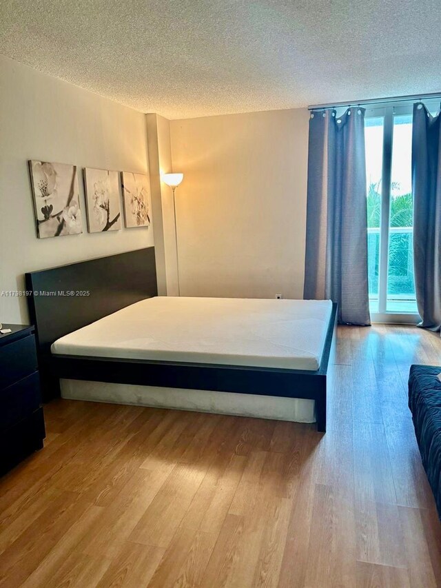 bedroom with a textured ceiling and wood finished floors