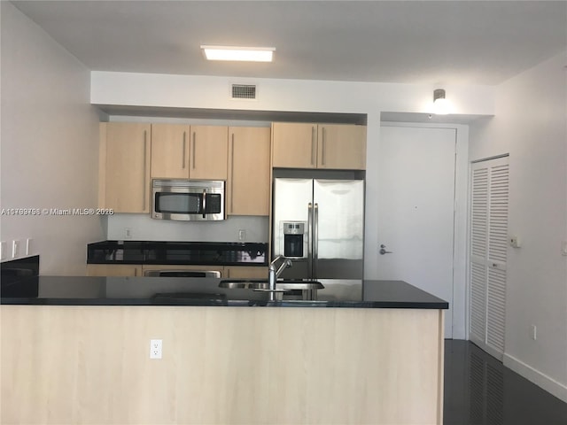 1111 SW 1st Ave Unit 2223-N, Miami, FL 33130 - kitchen featuring stainless steel appliances, light brown cabinetry, a sink, dark countertops, and baseboards