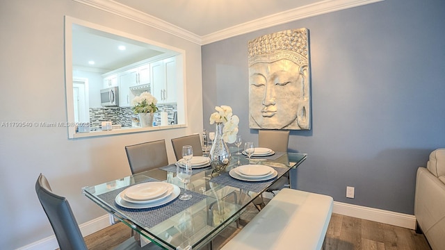 dining room with crown molding, baseboards, and wood finished floors