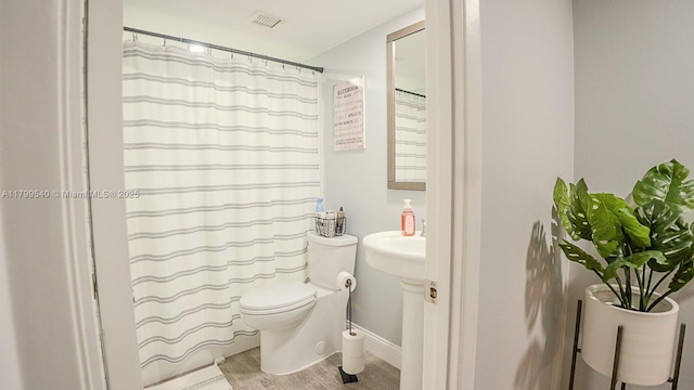 full bathroom featuring wood finished floors, toilet, a shower with curtain, and baseboards
