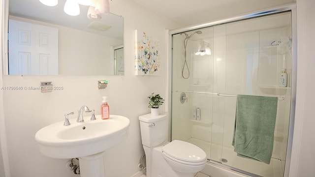 full bathroom with toilet, a stall shower, and a sink