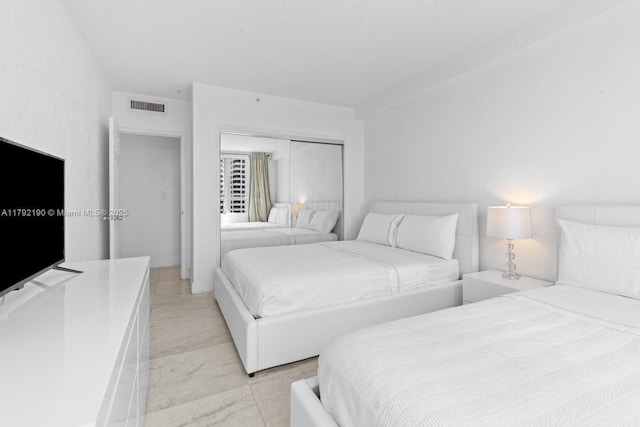 bedroom with light marble finish flooring and a closet