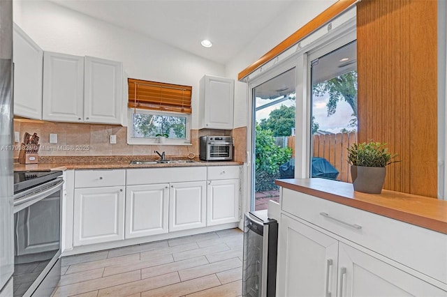 9821 W Fern Ln, Miramar, FL 33025 - kitchen featuring stainless steel electric range oven, decorative backsplash, white cabinets, recessed lighting, and a sink