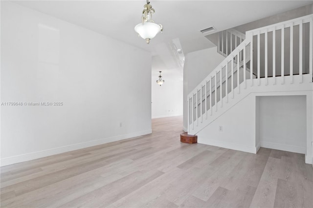 unfurnished living room featuring stairs, wood finished floors, and baseboards