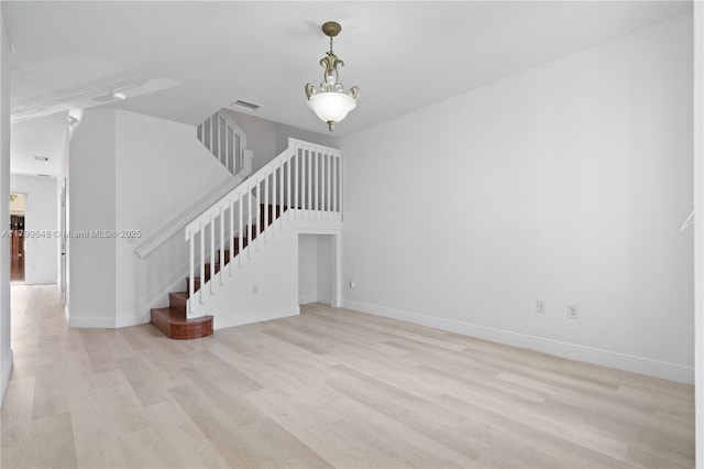 unfurnished living room featuring light wood-style floors, stairway, and baseboards