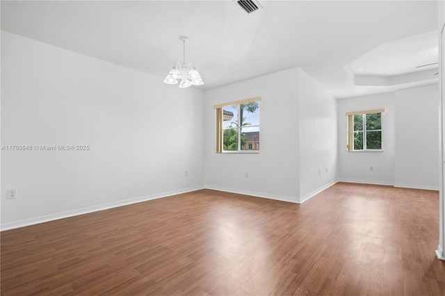 unfurnished room with a chandelier, wood finished floors, and baseboards