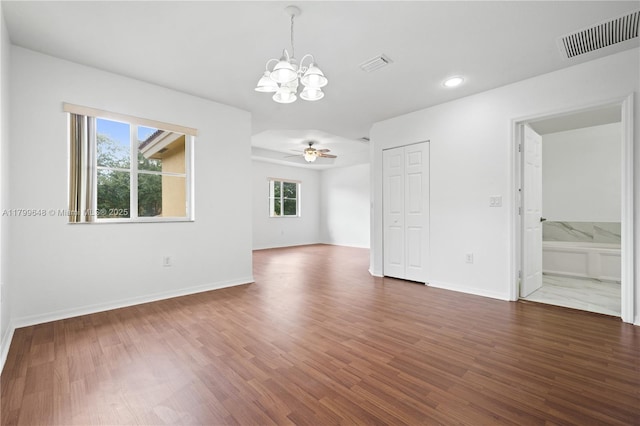 spare room featuring a chandelier, dark wood finished floors, a ceiling fan, baseboards, and recessed lighting