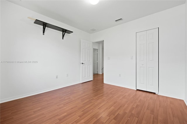 unfurnished bedroom with light wood-style flooring, baseboards, and a closet
