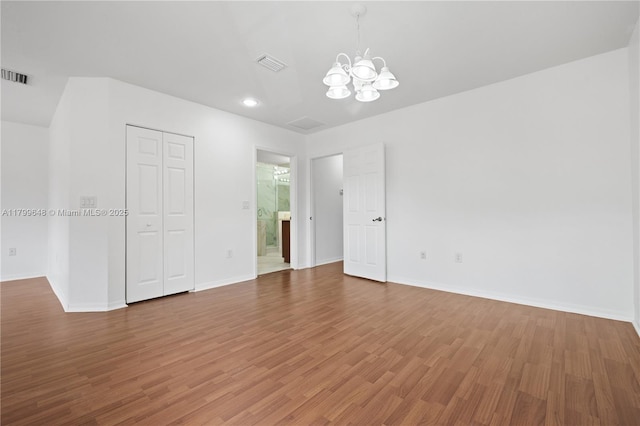 unfurnished room with a chandelier, wood finished floors, and baseboards