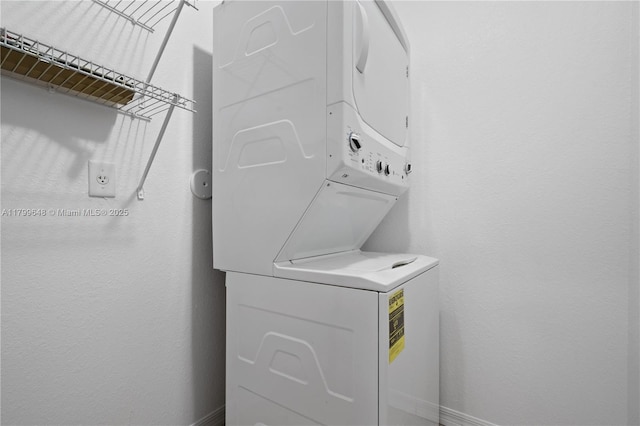laundry room with stacked washer / dryer and baseboards