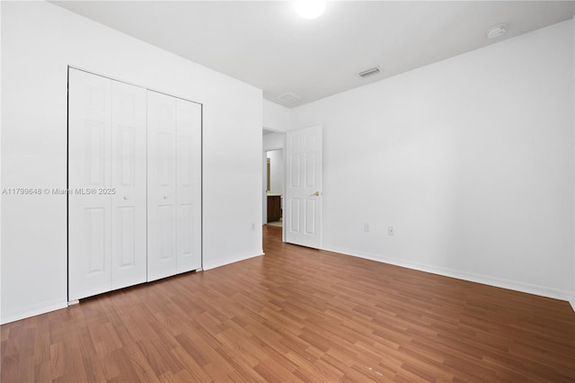 unfurnished bedroom with light wood-style floors, baseboards, and a closet