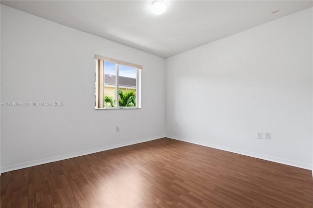 empty room featuring dark wood-style flooring and baseboards
