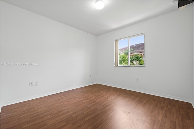 unfurnished room featuring baseboards and dark wood-type flooring