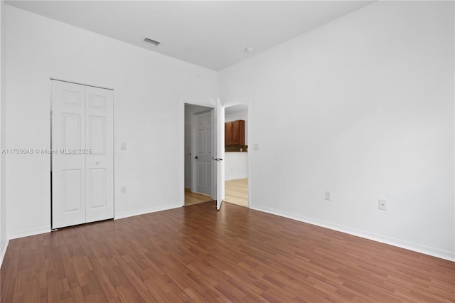 unfurnished bedroom featuring wood finished floors, baseboards, and a closet