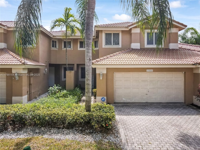 townhome / multi-family property with stucco siding, a tile roof, decorative driveway, and a garage