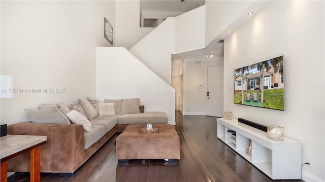 living room featuring dark wood finished floors, a high ceiling, and baseboards
