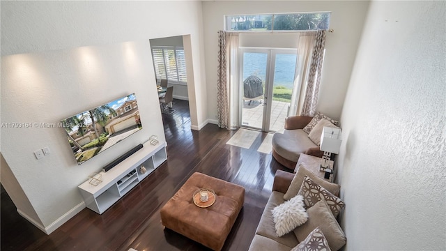 living area featuring baseboards, a textured wall, wood finished floors, and a high ceiling