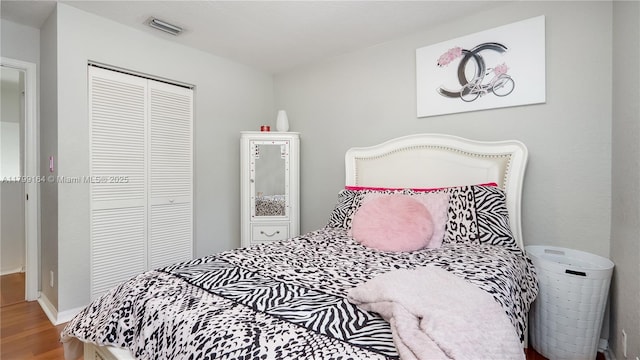 bedroom with wood finished floors and a closet