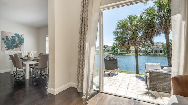doorway to outside with baseboards, wood finished floors, and a water view