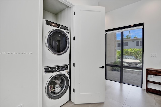 laundry area with stacked washing machine and dryer and light tile patterned floors