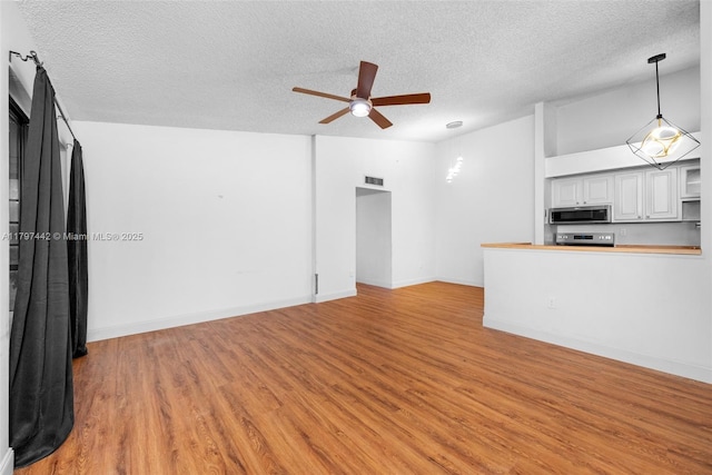 933 NE 199th St Unit 207, Miami, FL 33179 - unfurnished living room with a textured ceiling, ceiling fan, light wood-style floors, and baseboards