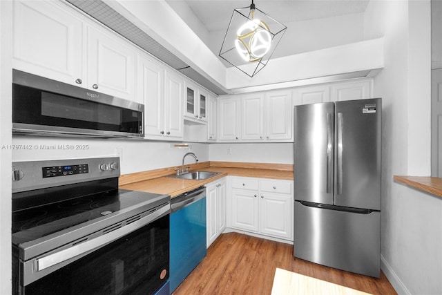 933 NE 199th St Unit 207, Miami, FL 33179 - kitchen featuring appliances with stainless steel finishes, a sink, light wood finished floors, white cabinets, and light countertops