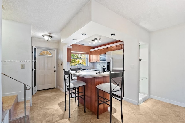 450 SE 7th St Unit 230, Dania Beach, FL 33004 - kitchen with stainless steel appliances, a textured ceiling, a breakfast bar, baseboards, and light countertops