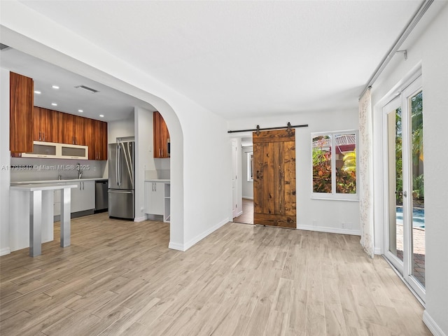 1730 NE 16th St, Fort Lauderdale, FL 33304 - unfurnished living room with a barn door, light wood-type flooring, arched walkways, baseboards, and recessed lighting