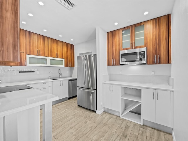1730 NE 16th St, Fort Lauderdale, FL 33304 - kitchen featuring appliances with stainless steel finishes, recessed lighting, light wood-type flooring, light countertops, and glass insert cabinets