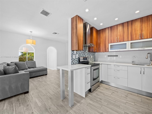 1730 NE 16th St, Fort Lauderdale, FL 33304 - kitchen with stainless steel range with electric cooktop, wall chimney range hood, a sink, light countertops, and arched walkways