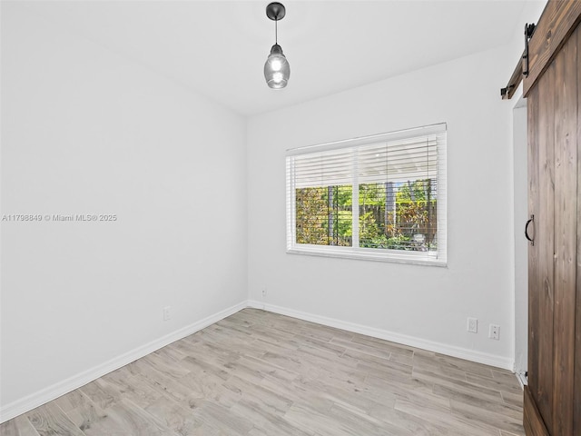 1730 NE 16th St, Fort Lauderdale, FL 33304 - unfurnished bedroom featuring a barn door, light wood-style flooring, and baseboards