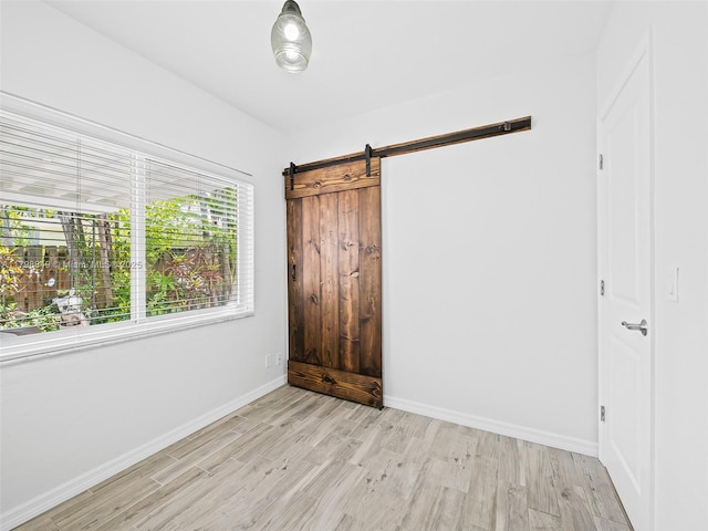 1730 NE 16th St, Fort Lauderdale, FL 33304 - unfurnished bedroom featuring light wood-style floors, baseboards, and a barn door