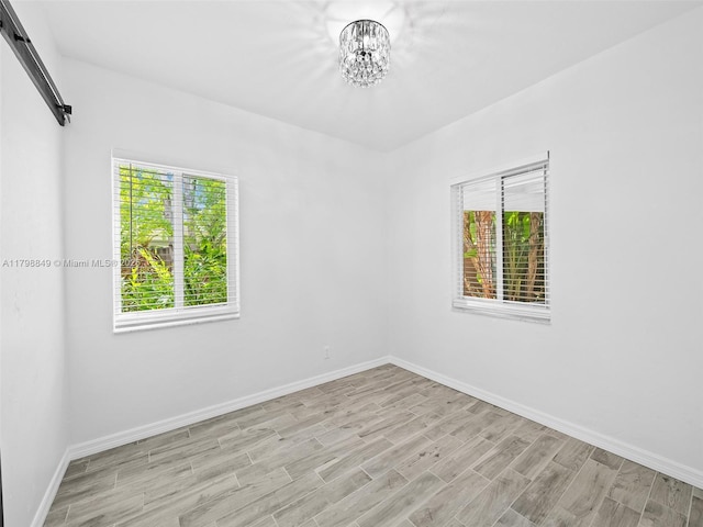 1730 NE 16th St, Fort Lauderdale, FL 33304 - spare room with a chandelier, light wood finished floors, baseboards, and a barn door