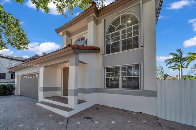 20076 NW 85th Ave, Hialeah, FL 33015 - view of side of home featuring stucco siding, a tiled roof, fence, and a garage