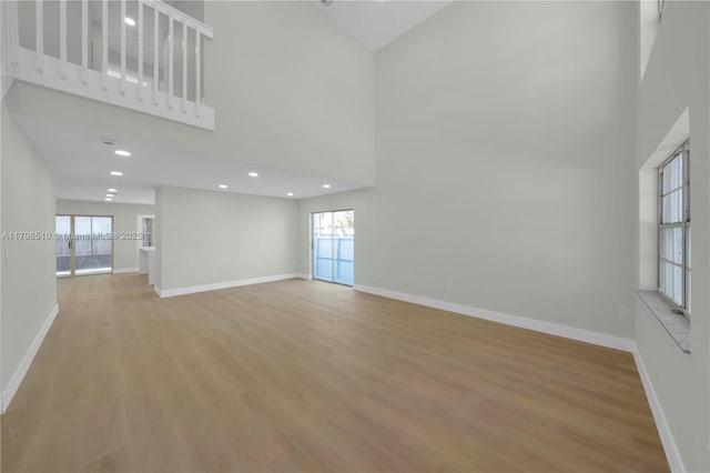 20076 NW 85th Ave, Hialeah, FL 33015 - unfurnished living room featuring a high ceiling, healthy amount of natural light, wood finished floors, baseboards, and recessed lighting
