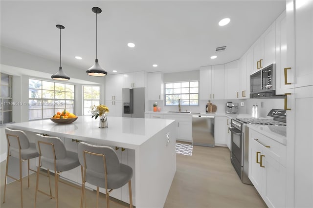 20076 NW 85th Ave, Hialeah, FL 33015 - kitchen with appliances with stainless steel finishes, a center island, light countertops, a sink, and white cabinetry