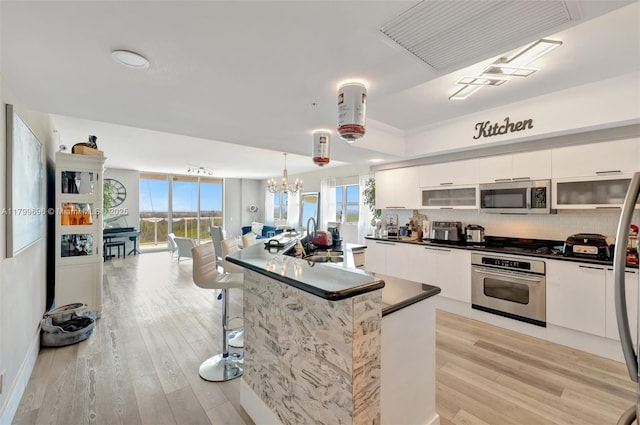 kitchen featuring stainless steel appliances, a sink, white cabinets, modern cabinets, and light wood-type flooring