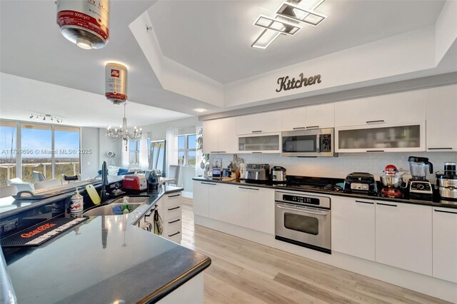 kitchen with stainless steel appliances, a sink, modern cabinets, and dark countertops