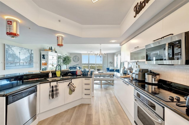 kitchen featuring stainless steel appliances, dark countertops, open floor plan, and light wood-style flooring