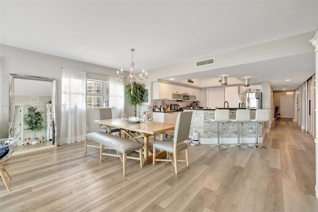 dining space with light wood-style flooring and a chandelier