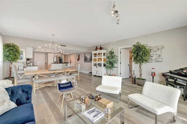 living room featuring a chandelier and light wood-type flooring