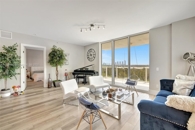 living room with light wood-style flooring and a wall of windows
